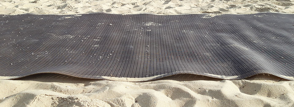 Cheminement PMR pour plage qui gondole Un cheminement pour PMR sur une plage. La photo prise sur le côté montre que le produit gondole induisant un risque de chute