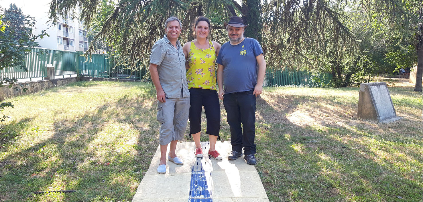Les porteurs du projet CAU-mobility Photo panoramique dans un parc arboré des 3 porteurs du projet sur une pelouse, ils se tiennent debouts sur le dispositif de cheminement placé sur l'herbe, de gauche à droite, Rui PEREIRA, Amélie GARBAN et Christian ROCHE