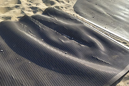 Cheminement PMR pour plage qui se plisse à l’usage Un cheminement pour PMR sur une plage. La photo prise du haut montre que le produit plisse avec l’usage induisant un risque de chute