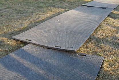 Plaque de roulage avec une accessibilité dangereuse Des plaques de roulage placées sur un terrain herbeux. Les plaques sont décalées, incurvées et les extrémités qui se superposent : une accessibilité dangereuse